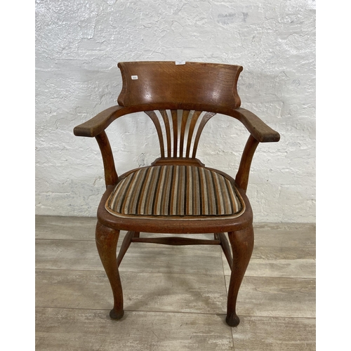 123 - An early 20th century oak desk chair on cabriole supports with lower stretchers and upholstered seat... 