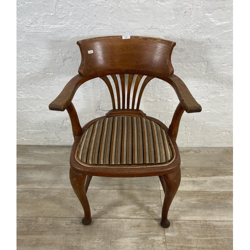 123 - An early 20th century oak desk chair on cabriole supports with lower stretchers and upholstered seat... 