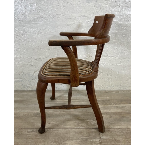 123 - An early 20th century oak desk chair on cabriole supports with lower stretchers and upholstered seat... 