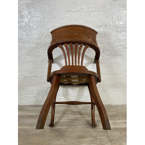 123 - An early 20th century oak desk chair on cabriole supports with lower stretchers and upholstered seat... 