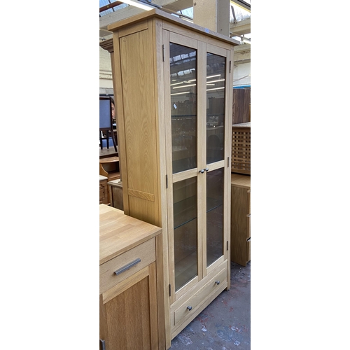 141 - A light oak display cabinet with one lower drawer, two glazed doors and four internal shelves - appr... 