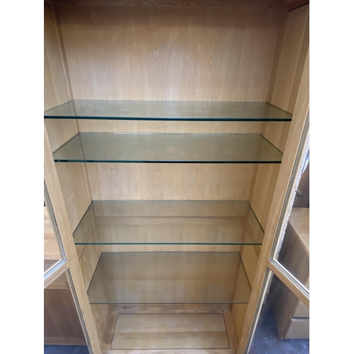 141 - A light oak display cabinet with one lower drawer, two glazed doors and four internal shelves - appr... 