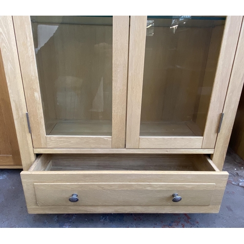 141 - A light oak display cabinet with one lower drawer, two glazed doors and four internal shelves - appr... 