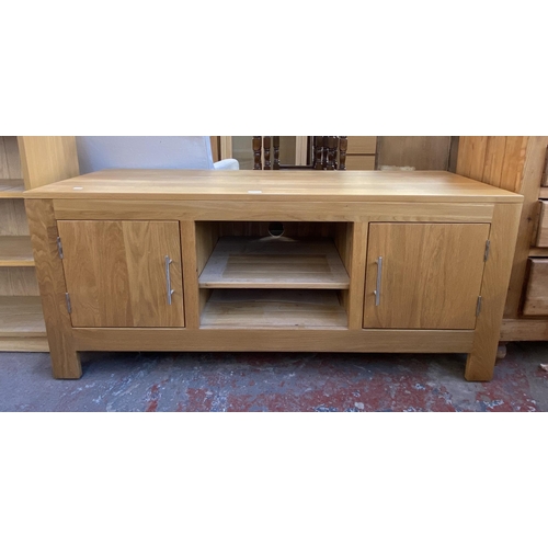 165 - A solid oak TV stand with two cupboard doors and one shelf - approx. 61cm high x 138.5cm wide x 50cm... 