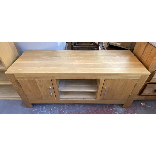 165 - A solid oak TV stand with two cupboard doors and one shelf - approx. 61cm high x 138.5cm wide x 50cm... 