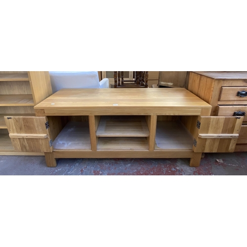 165 - A solid oak TV stand with two cupboard doors and one shelf - approx. 61cm high x 138.5cm wide x 50cm... 