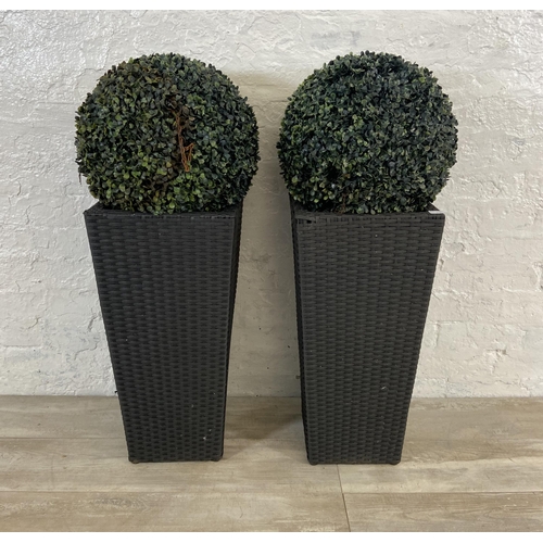 172 - Four items, a pair of black plastic rattan effect garden planters and a pair of artificial buxus pla... 