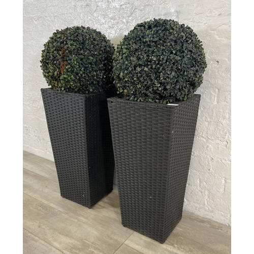 172 - Four items, a pair of black plastic rattan effect garden planters and a pair of artificial buxus pla... 