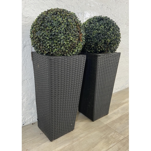 172 - Four items, a pair of black plastic rattan effect garden planters and a pair of artificial buxus pla... 