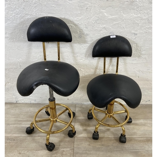 78 - A pair of black faux leather and gilt metal swivel saddle chairs