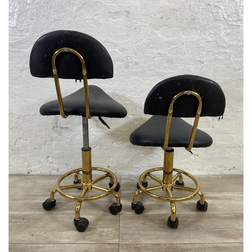 78 - A pair of black faux leather and gilt metal swivel saddle chairs