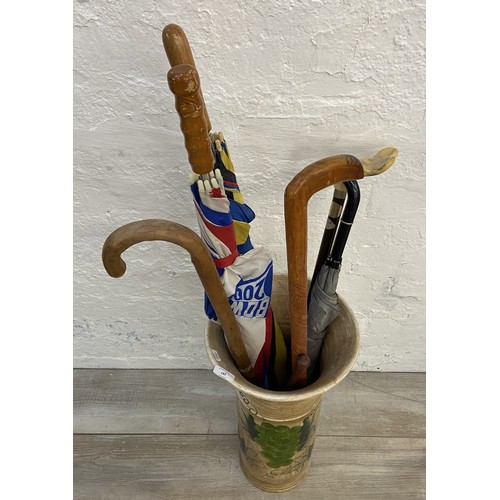 182 - A hand painted ceramic stick stand with grape design containing three umbrellas, three walking stick... 