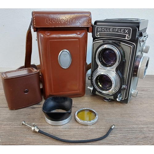 A cased 1958 Franke & Heidecke Rolleiflex T model 1 medium format 6x6 TLR camera for 120 film fitted with Carl Zeiss Tessar 1:3.5 f=75mm taking lens, Heidosmat 1:2.8/75 viewing lens and Synchro-Compur shutter (serial number 2100050)