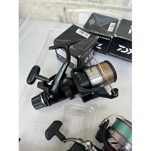 1002 - A box containing fishing reels and spools to include Shimano Baitrunner 8000, Shimano Baitrunner 600... 