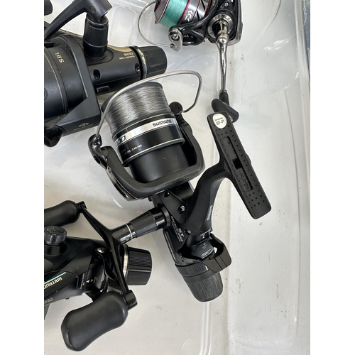 1002 - A box containing fishing reels and spools to include Shimano Baitrunner 8000, Shimano Baitrunner 600... 