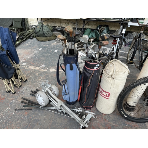 1022 - A collection of vintage sporting items, two golf bags, one manual trolley, a large collection of clu... 