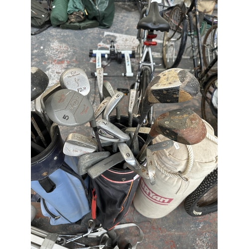 1022 - A collection of vintage sporting items, two golf bags, one manual trolley, a large collection of clu... 