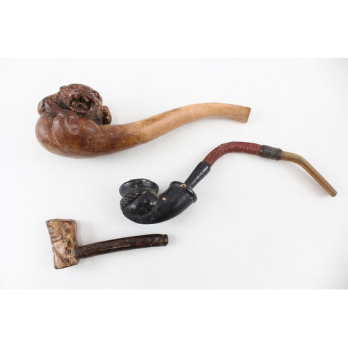 2267 - Three antique smoking pipes to include grotesque clay gargoyle, 18th century petrified wood etc.