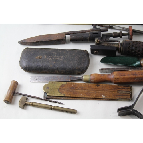 562 - A collection of vintage tools to include leather tape measures, corkscrew, spirit level etc.