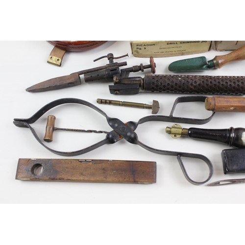 562 - A collection of vintage tools to include leather tape measures, corkscrew, spirit level etc.