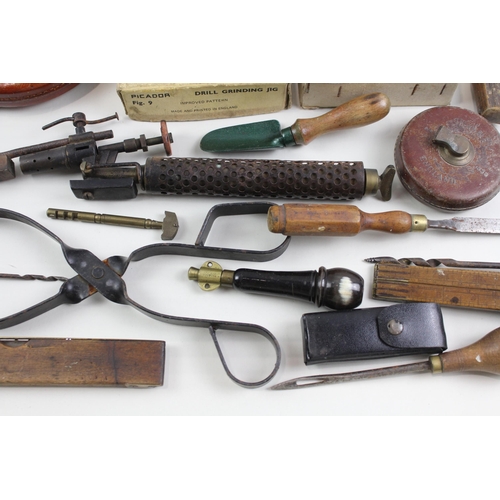 562 - A collection of vintage tools to include leather tape measures, corkscrew, spirit level etc.