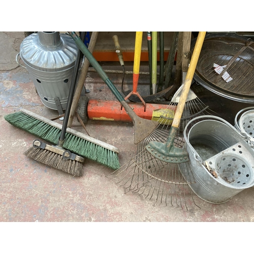 1034B - A collection of items to include vintage sheet metal roller, fire pit, galvanised mop buckets, rakes... 