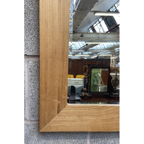 246 - A modern oak framed over mantel bevelled edge wall mirror - approx. 78cm high x 108cm wide