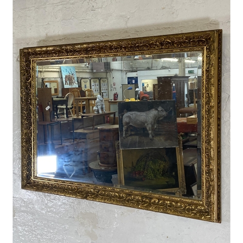 284 - A gilt framed bevelled edge overmantel wall mirror - approx. 74cm high x 100cm wide