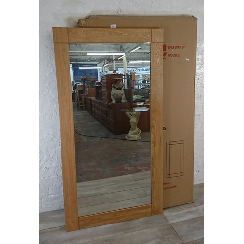 107 - A boxed JB Global oak framed wall mirror - approx. 150cm x 80cm