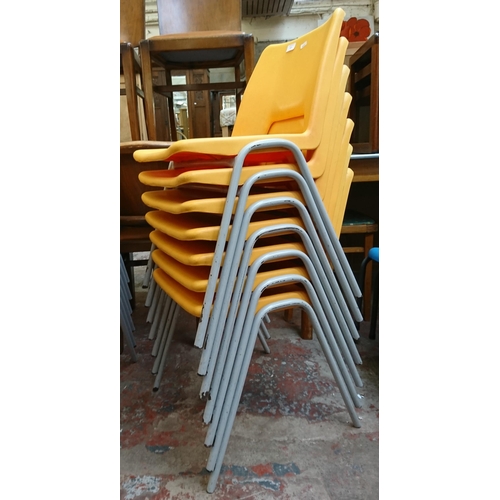 123 - Thirteen mid/late 20th century yellow plastic and tubular metal stacking children’s school chairs