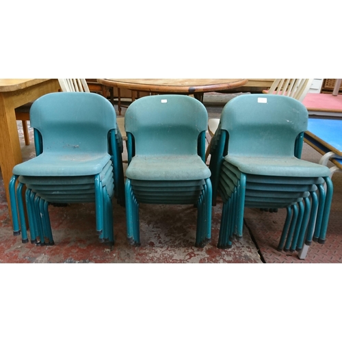 124 - Twenty one mid/late 20th century green plastic and tubular metal stacking children's school chairs