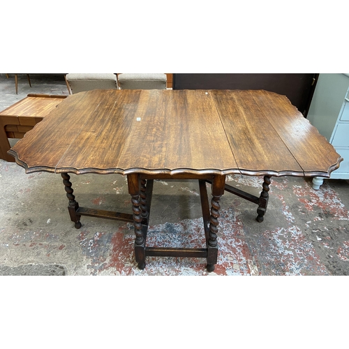 80 - An early 20th century oak pie crust edge drop leaf gate leg dining table on barley twist supports