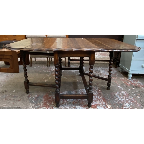 80 - An early 20th century oak pie crust edge drop leaf gate leg dining table on barley twist supports