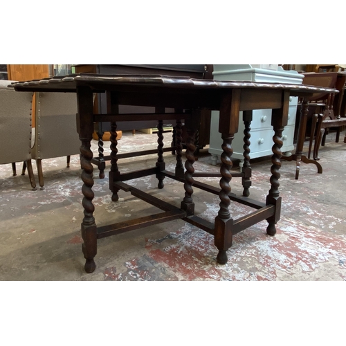 80 - An early 20th century oak pie crust edge drop leaf gate leg dining table on barley twist supports