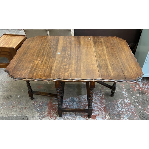 80 - An early 20th century oak pie crust edge drop leaf gate leg dining table on barley twist supports