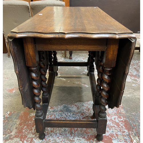 80 - An early 20th century oak pie crust edge drop leaf gate leg dining table on barley twist supports