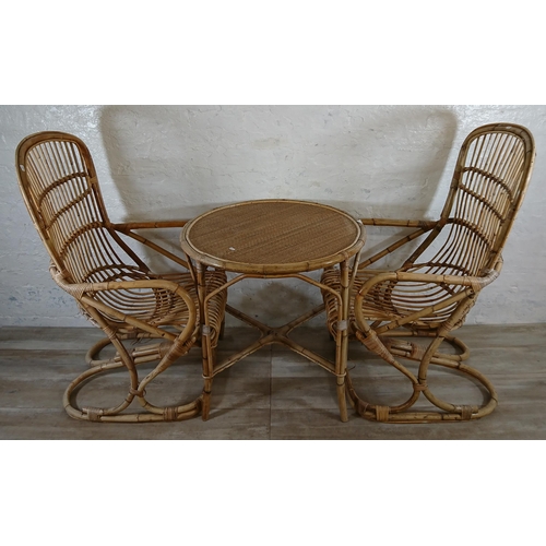 165 - A mid 20th century wicker and bamboo four piece dining suite comprising circular table and three arm... 