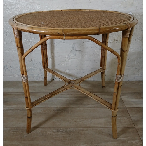 165 - A mid 20th century wicker and bamboo four piece dining suite comprising circular table and three arm... 