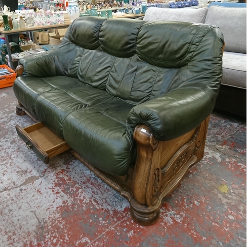 242 - A carved oak and green leather three seater sofa