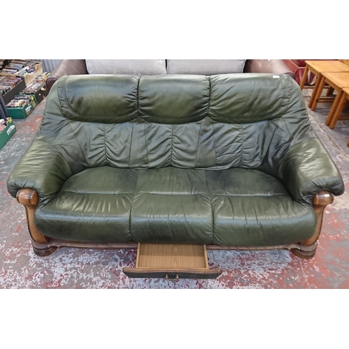 242 - A carved oak and green leather three seater sofa