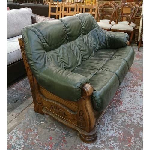 242 - A carved oak and green leather three seater sofa