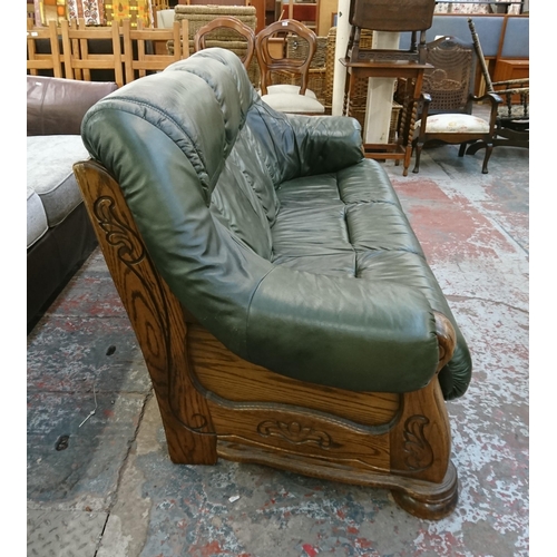 242 - A carved oak and green leather three seater sofa