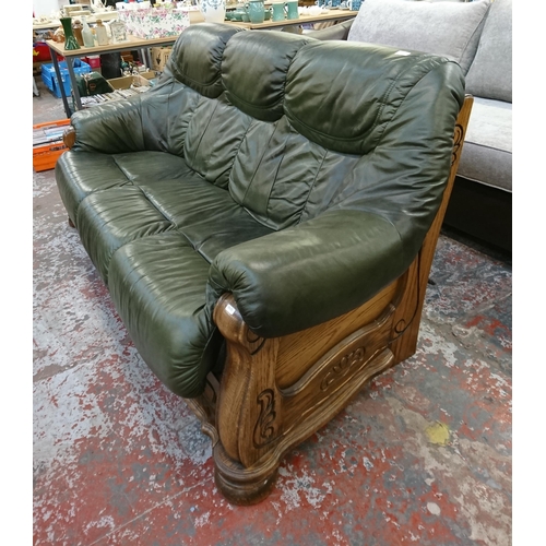 242 - A carved oak and green leather three seater sofa