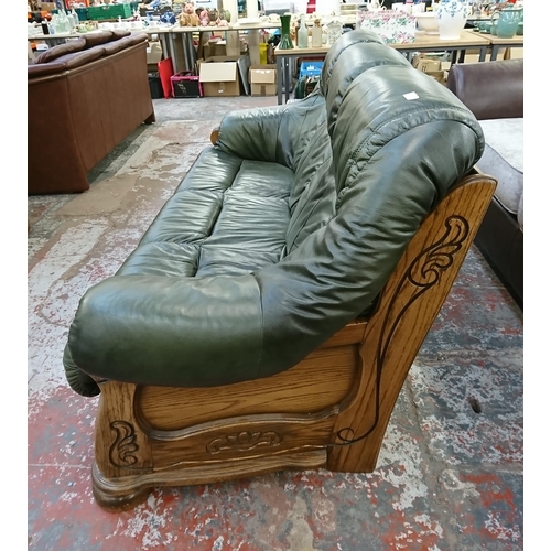 242 - A carved oak and green leather three seater sofa