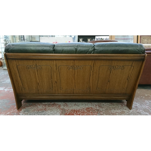 242 - A carved oak and green leather three seater sofa