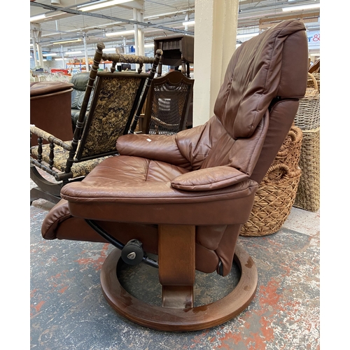 242A - An Ekornes Stressless cognac brown leather and beech swivel reclining armchair and footstool