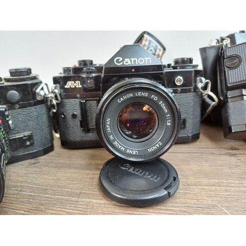 615 - Five Canon A-1 35mm SLR cameras fitted with Canon FD lenses, one 1:1.4 50mm, Power Winder A and Data... 