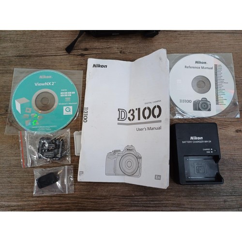 647 - A Nikon D3100 DSLR camera body with charger, software discs and instruction manual