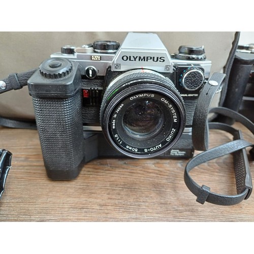 667 - A collection of Olympus items to include five OM10 35mm SLR cameras, Zuiko lenses, flashes etc.