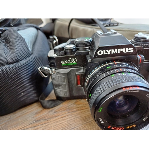 675 - Five Olympus 35mm SLR cameras, one OM30 with instruction manual, three OM40 Program and one OM101 Po... 